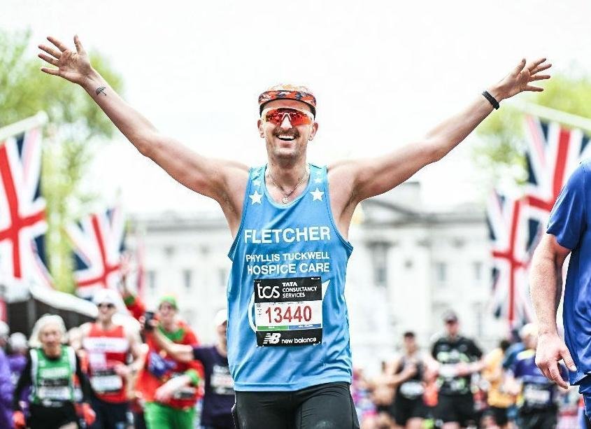 A marathon runner finishing with her arms held wide in celebration