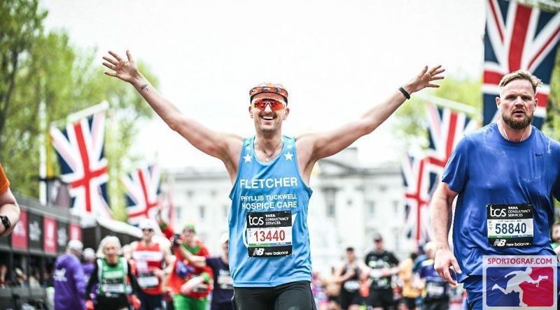 A runners completing the London Marathon with her hands up