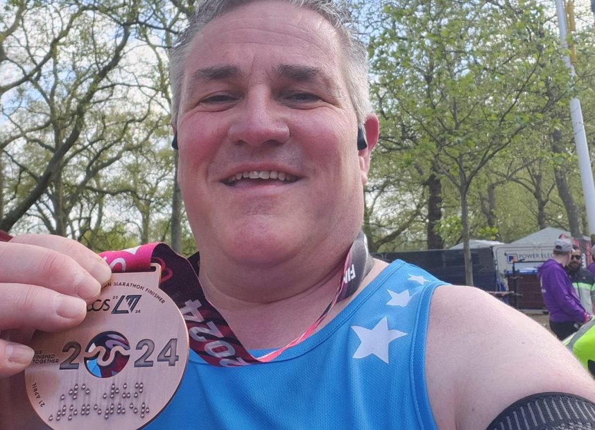 A marathon runner holding his medal to the camera