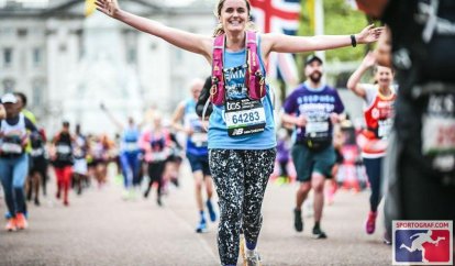 A marathon runner finishing with her arms held wide in celebration