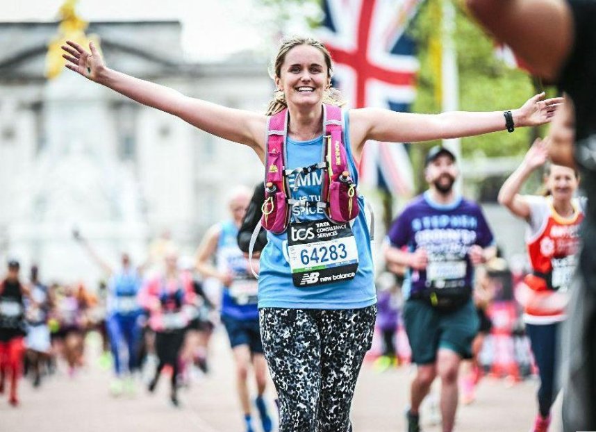 A runner finishing the marathon with her arms held wide in celebration