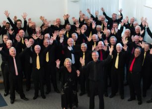 A smartly dressed choir waving to the camera