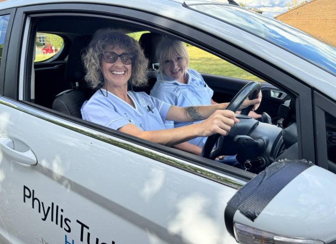 A nurse smiling at a patients front door