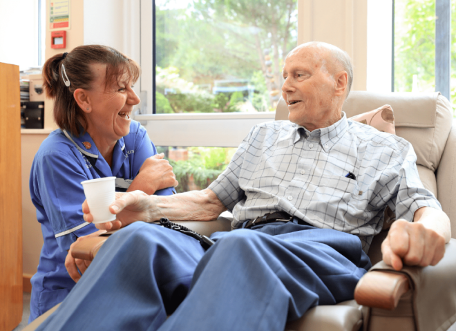 A nurse kneeling next to a patient and laughing