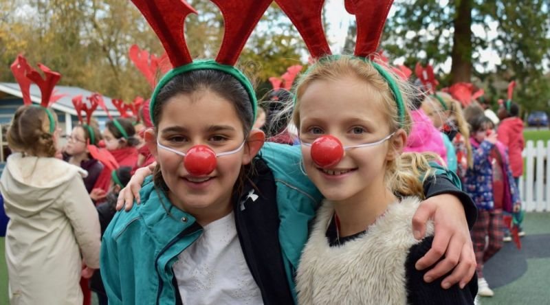 Two schoolgirls wearing reindeer antlers and red noses