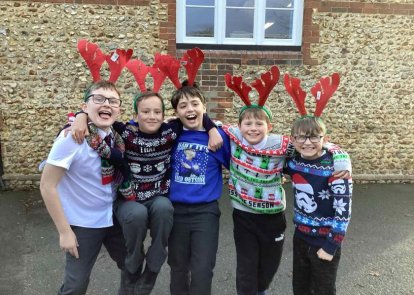 Children wearing Christmas jumpers and reindeer antlers