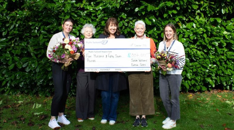 People standing with cheque and flowers