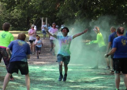 A person running, with people throwing powder paint