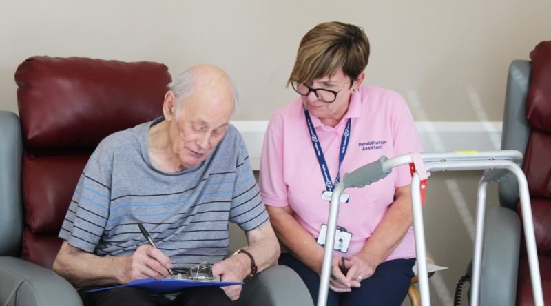Patient filling in form with rehabilitation assistant