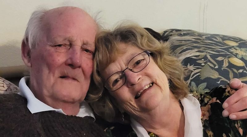 A couple hugging and smiling at the camera