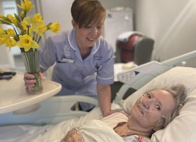 A nurse kneeling next to a patient and laughing