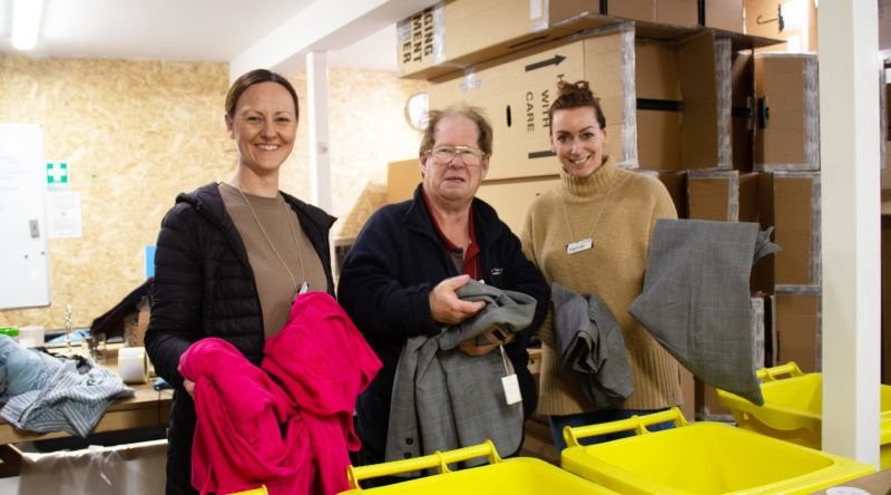 Group of people sorting through items, smiling at camera