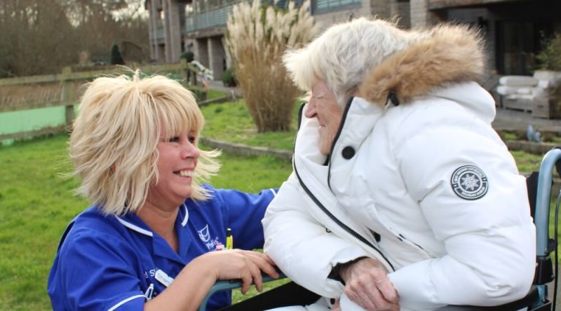 A nurse kneeling next to a patient and smiling
