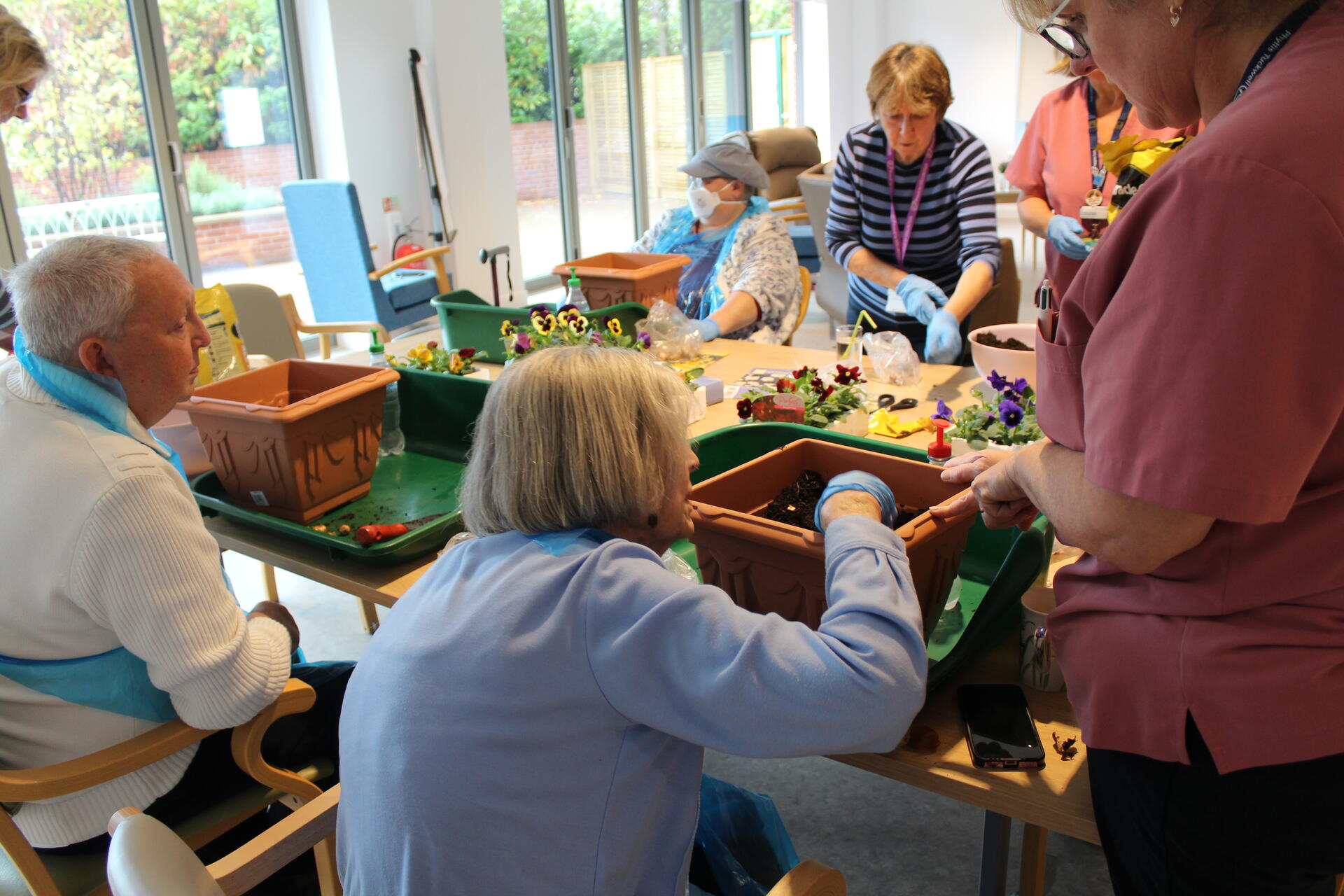 People sitting around a table planting flowers in pots